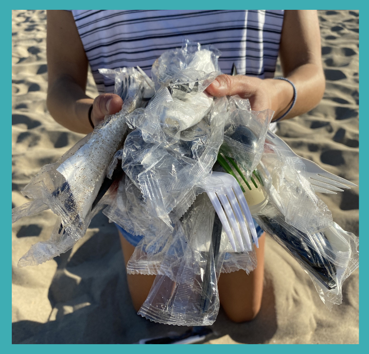 hands holding various utensil packs found on the beach